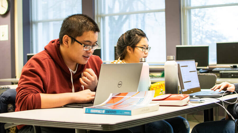 Students working with textbooks and laptops on homeworkin the the tutoring center