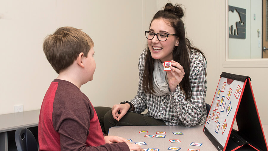 A student helps a child to learn words using pictures.