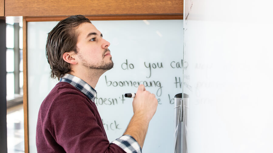 A student begins writing on a white board with an erasable felt pen.