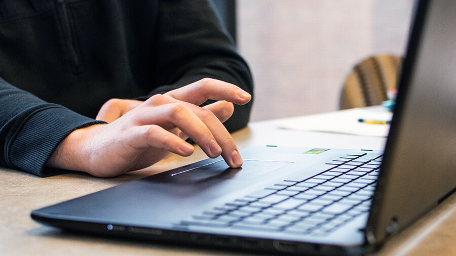 Hands on a trackpad of of a laptop.