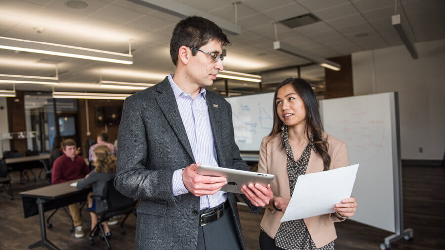 Two faculty members talking about advising over an iPad
