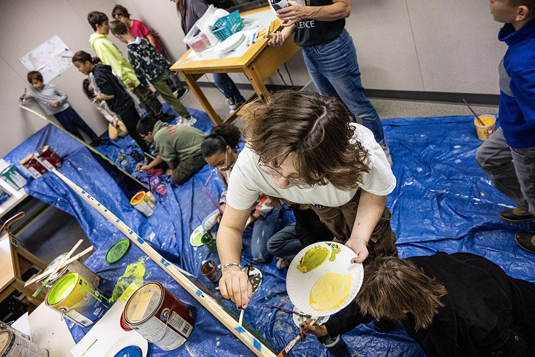 A student paints on a canvas.