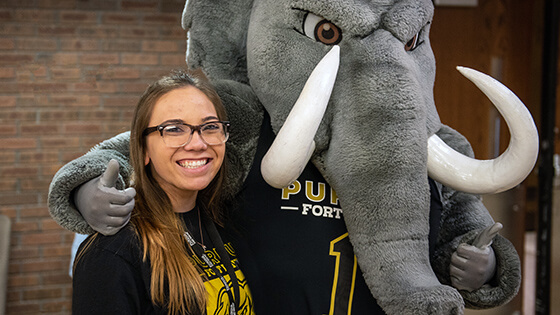 A student poses with Don Mastodon during a spirit event.