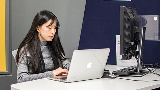 A student works on a computer in a campus department.