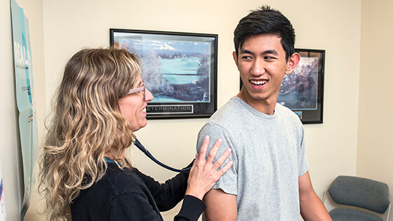 The campus nurse practitioner checks a patient’s lungs.