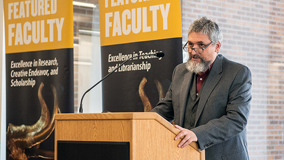 A faculty member speaks at a podium during a Featured Faculty event.