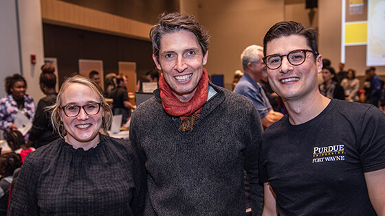 Three faculty pose for a photo during a gathering in the Walb Student Union International Ballroom.