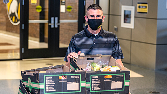 A student poses with a box of food items for the Pantry, a campus food bank.