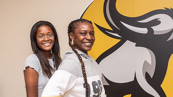 Prospective students pose in front of a mastodon wall graphic.