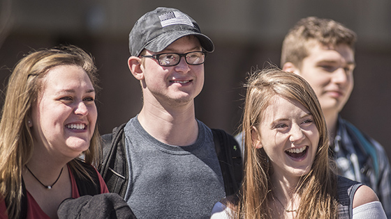 A group of students laugh and smile while outside.