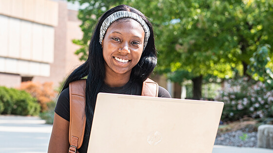 A student works on a laptop outside during summer classes.