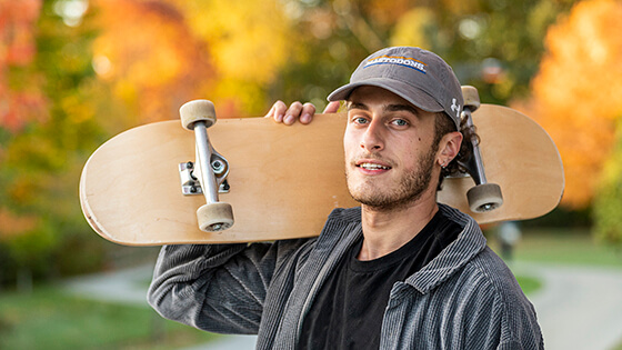 PFW student holds a skateboard while headed to class.