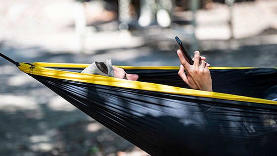 A student relaxes in a hammock on campus between classes.