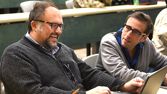 Two students reading the facebook on a laptop in a lecture hall.