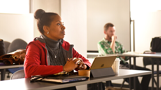 A student attentively sits at a table during a lecture.