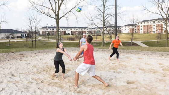 Student playing sand volleyball at student housing court