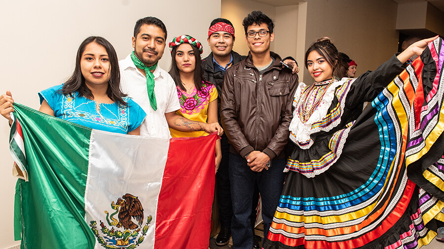 Students posing for a photo holding Mexico's flag