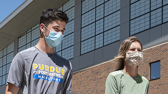 Two Purdue Fort Wayne students walk across campus wearing masks.
