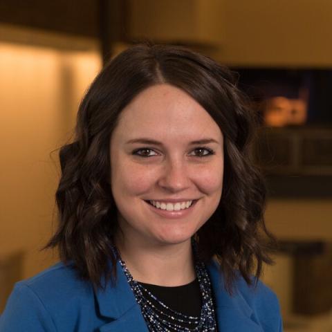 Kristin Barker, Clinical Assistant Professor in the Department of Human Services smiling in front of a blurred background. 