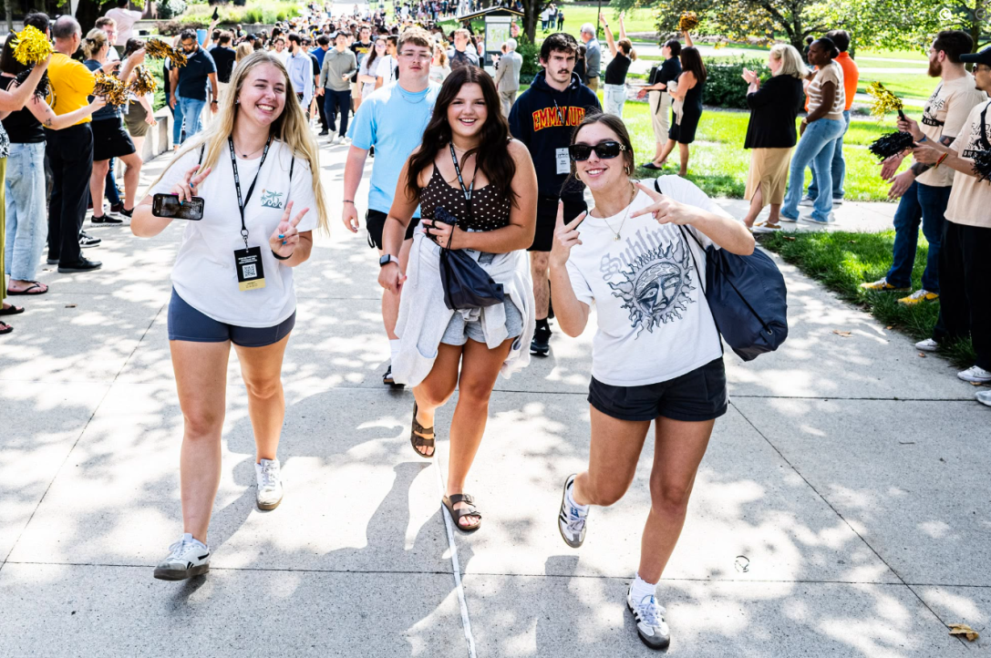 Students smiling at camera on sidewalk