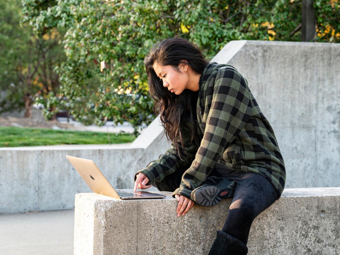 Female student sitting and studying outdoors.
