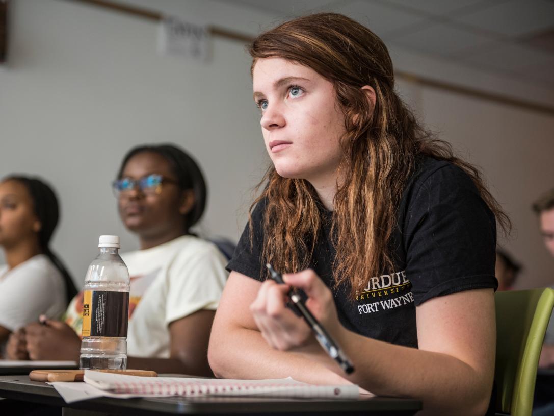Student taking notes wears Purdue Fort Wayne shirt.