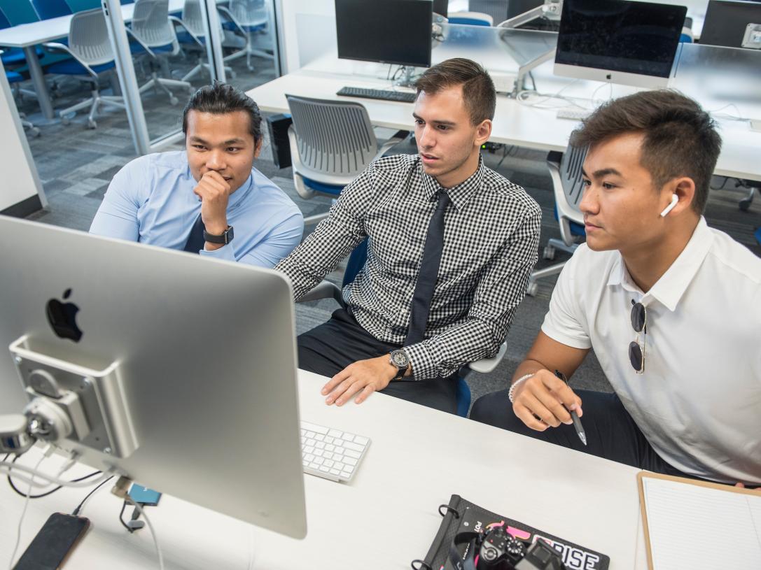 Students work together on a project at a computer