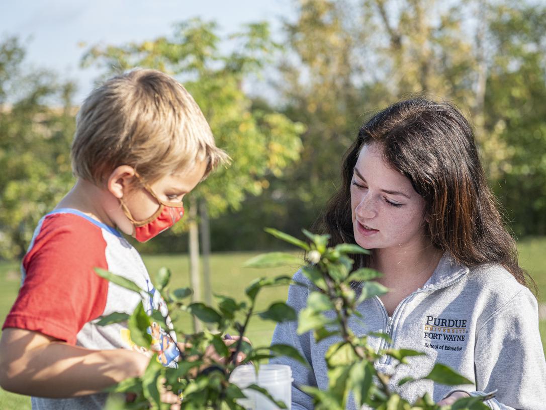 An education student with an elementary child in the Extension garden