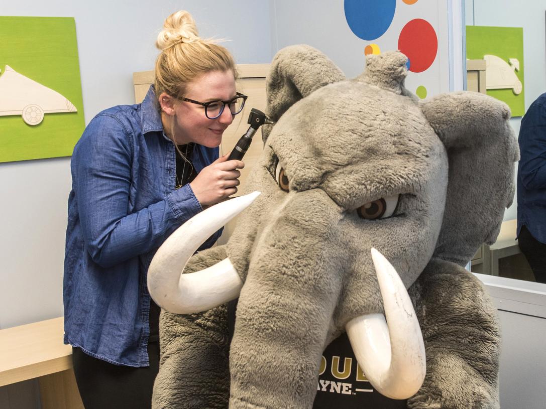 A CSD student gives Don the Mastodon an ear exam