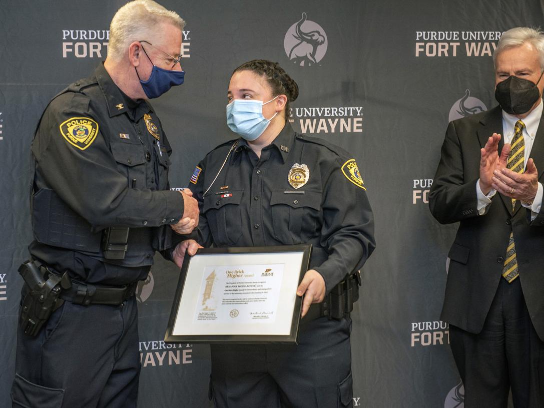 Officer BreAnne Wojnarowski is presented with the One Brick Higher Award by Chief John Cox