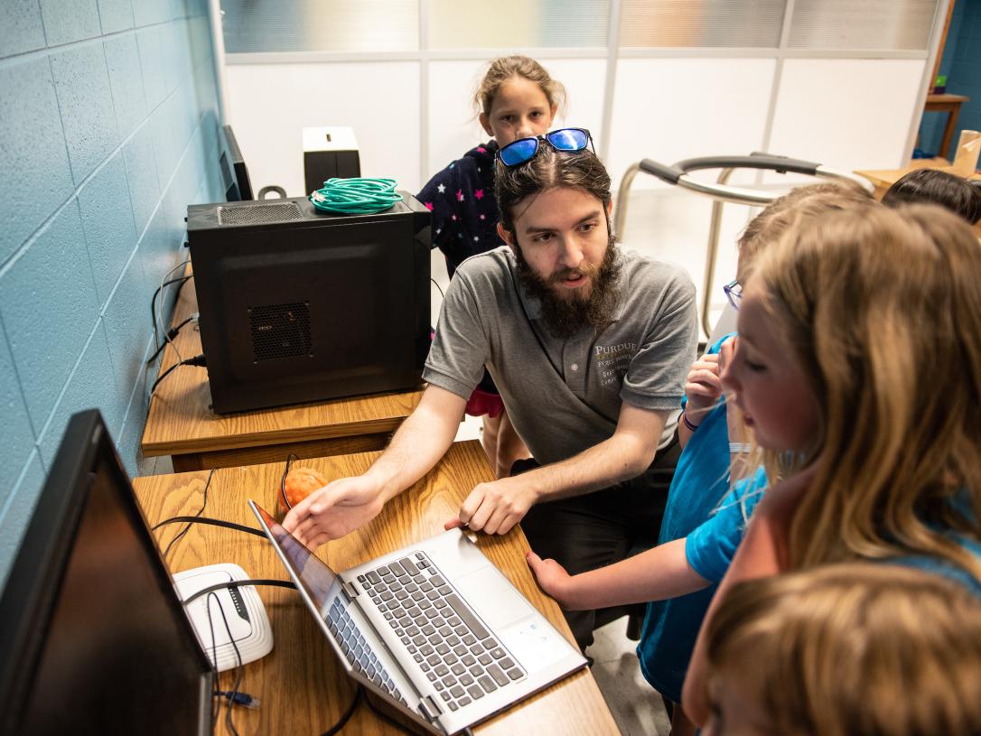 Student showing children a computer