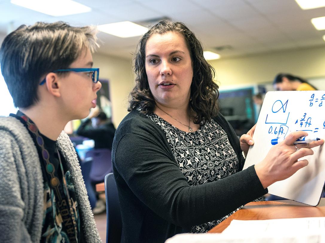 A student teacher is is instructing a student in a classroom