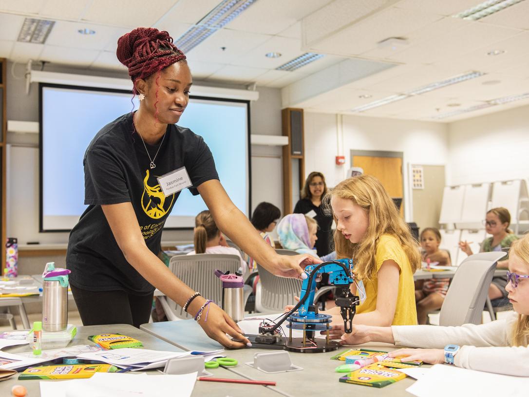 A student and teacher work with a robotic arm