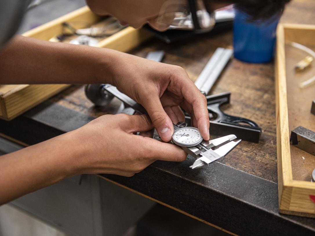 A student ls learning how to use a dial caliper