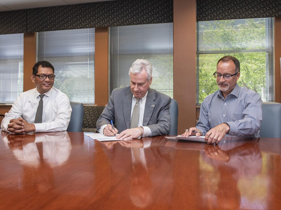 Chancellor Ron Elsenbaumer (middle) and Dan Florin (right) sign a memorandum of understanding between Purdue Fort Wayne and Catholic Charities while Nyein Chan looks on.