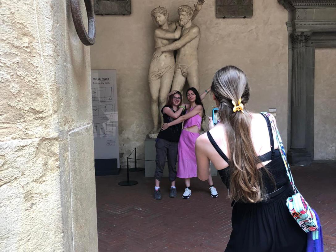 Art students are having their photo taken in front of a statue