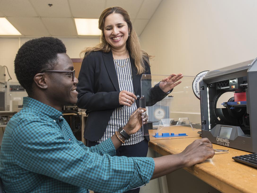 Professor Behin Elahi works with a student at a 3D printer
