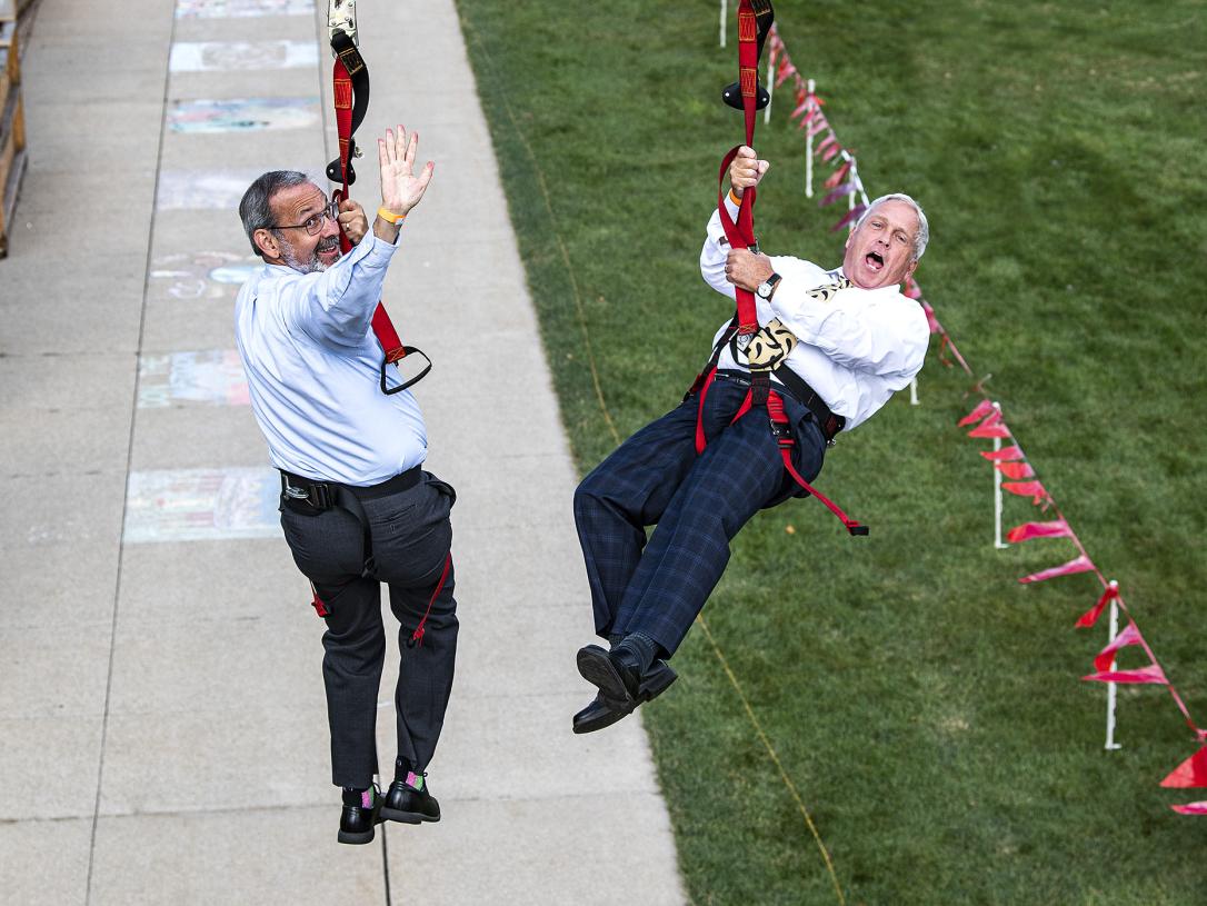 Deans Ron Friedman and John O'Connell head down the zipline at the annual Dons Picnic on the Lawn