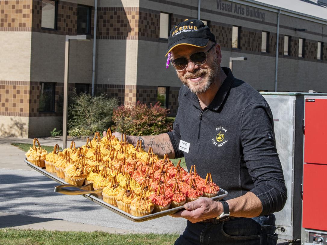 Food manager Ben Grubisich holds a tray of large cupcakes
