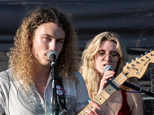 Two members of the band man of the Flood are singing. One is playing guitar.