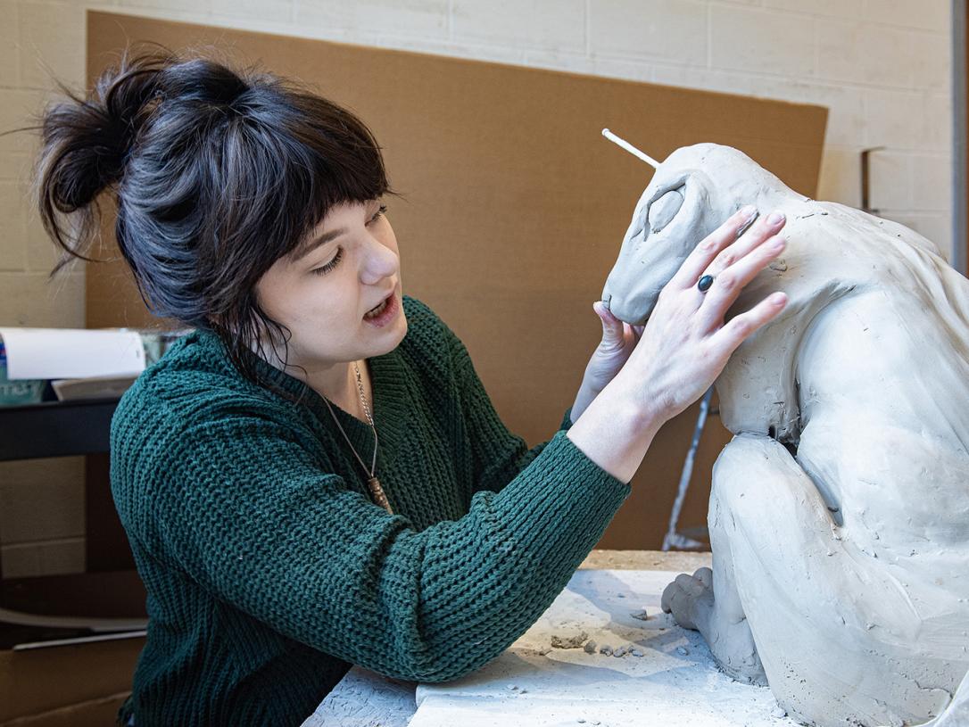 Emily Whisman is sculpting in an art studio