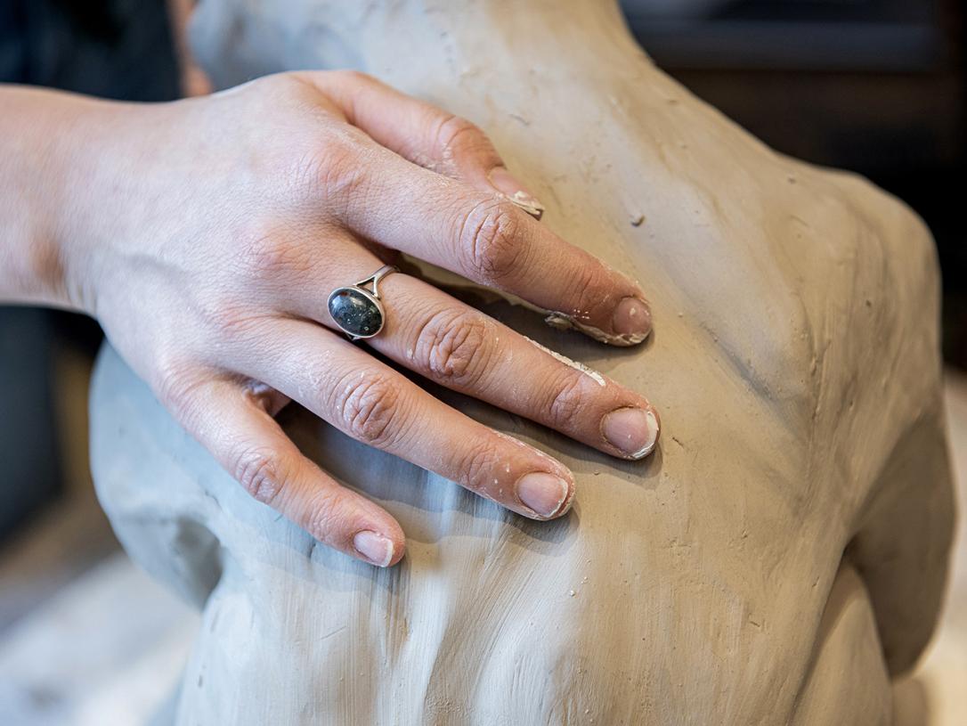 Emily Whisman is sculpting in an art studio