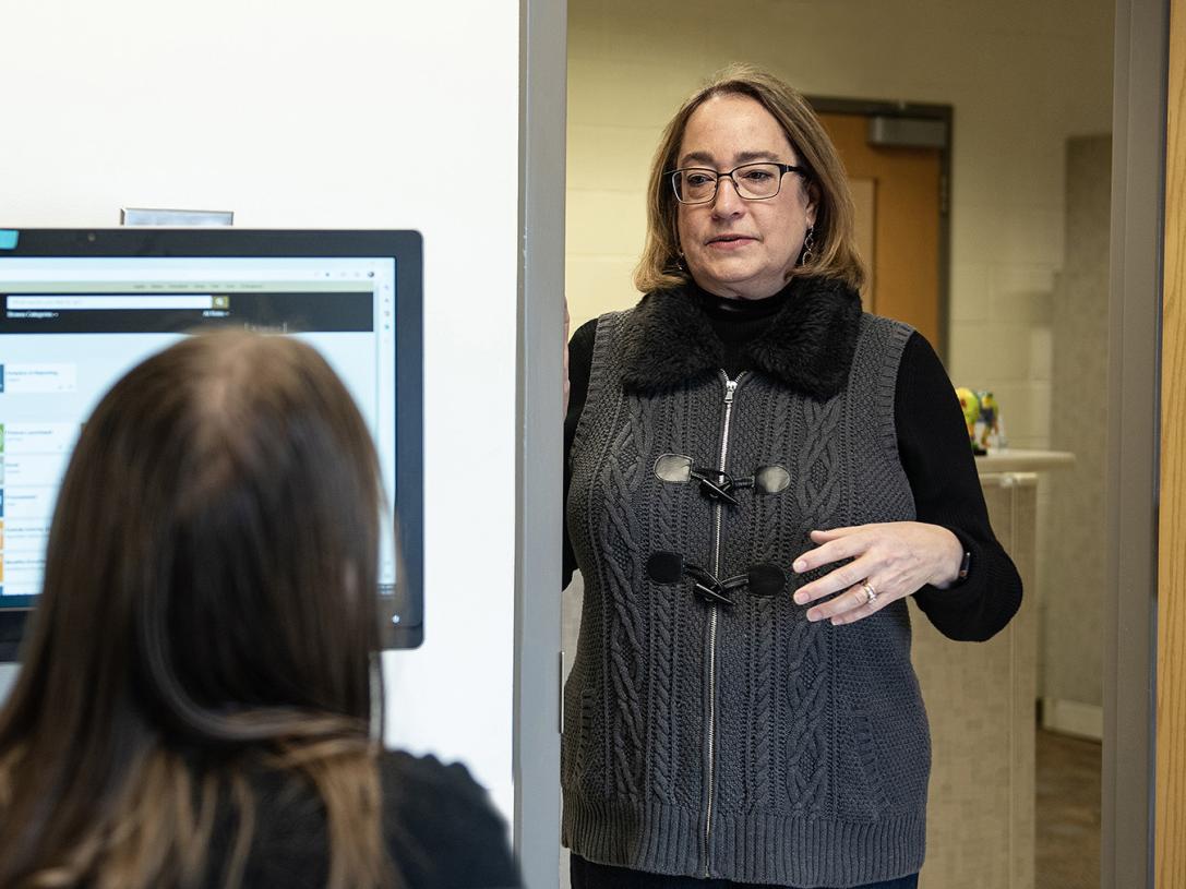 Jana Lece is standing in a doorway while talking to a coworker