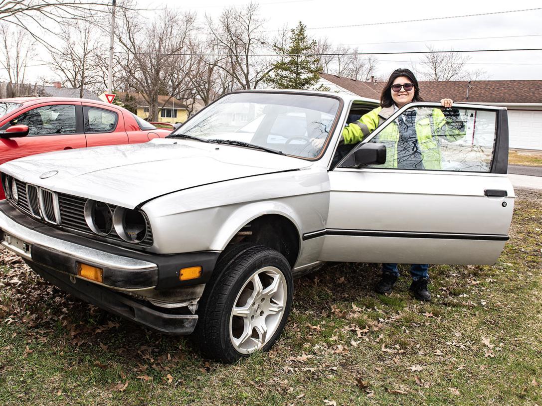 A polytechnic student is standing beside a BMW car.