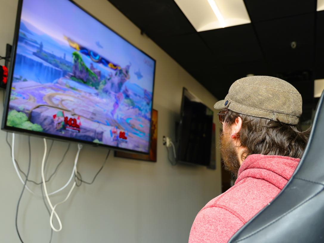 Nicholas Shatzer is playing a video game in the esports lab.