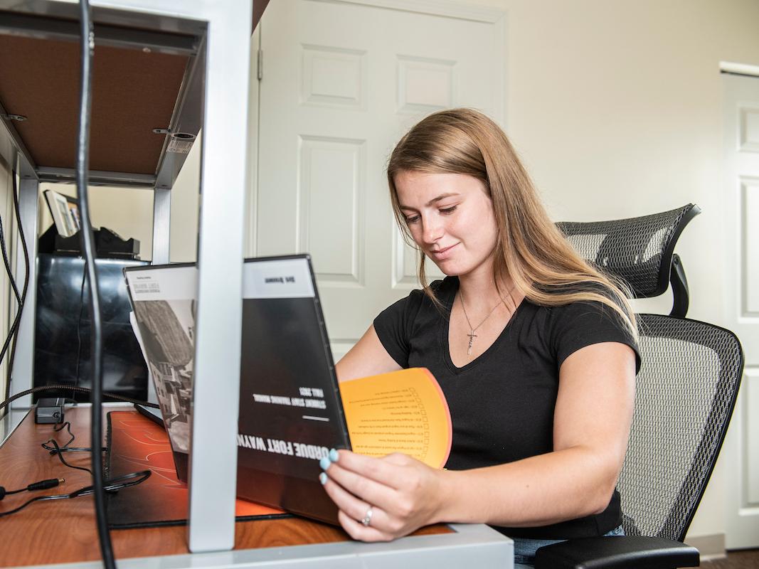 Student sits at their desk in student housing.