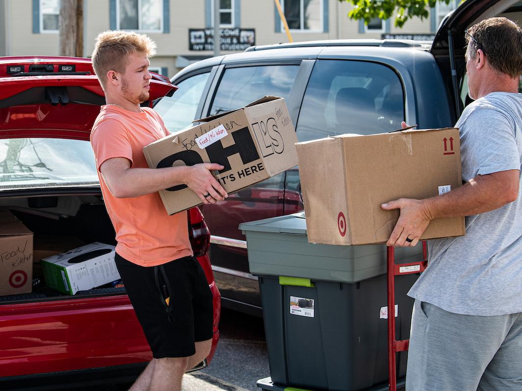 A student moves boxes in with a parent on move-in day.