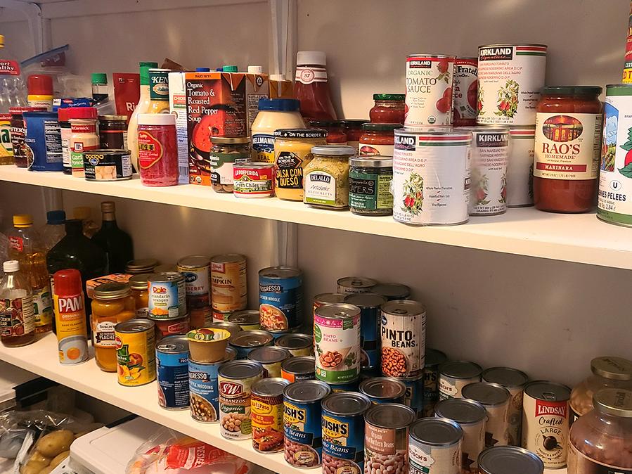 Close up of canned goods on a white pantry shelf