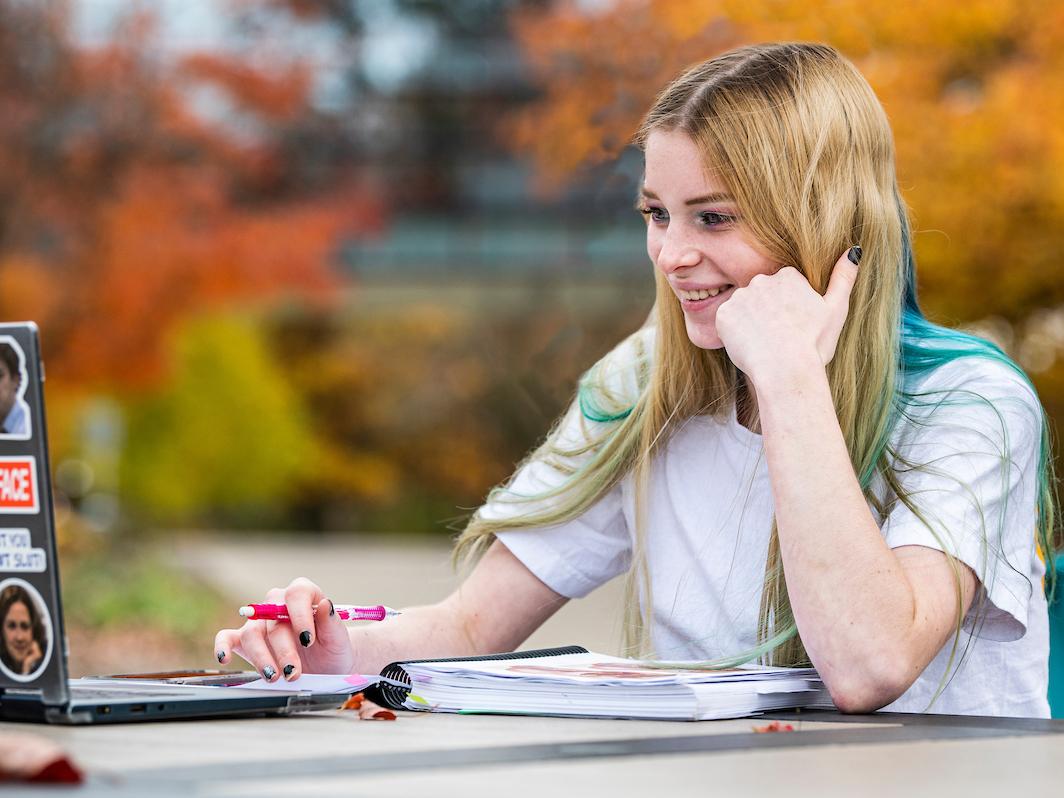 A student studies outside and works on a laptop.