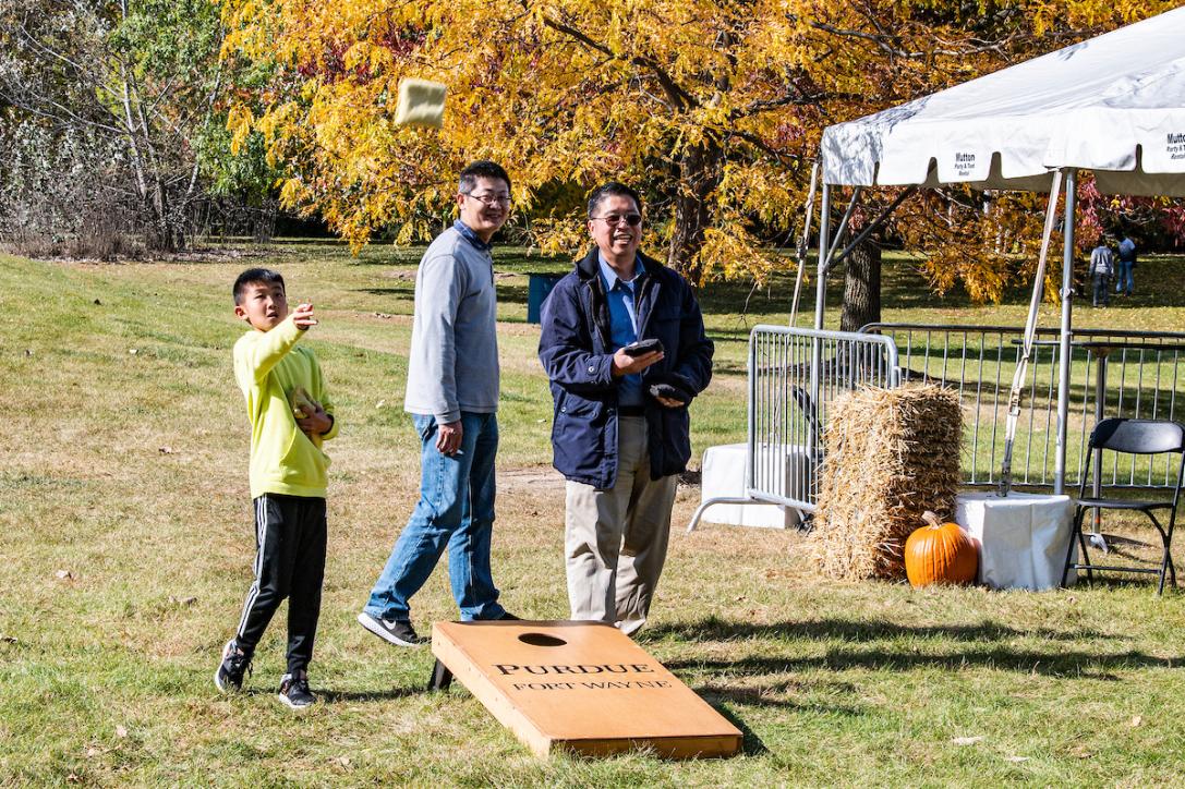 Family plays corn hole at the Mastodon Family Picnic.